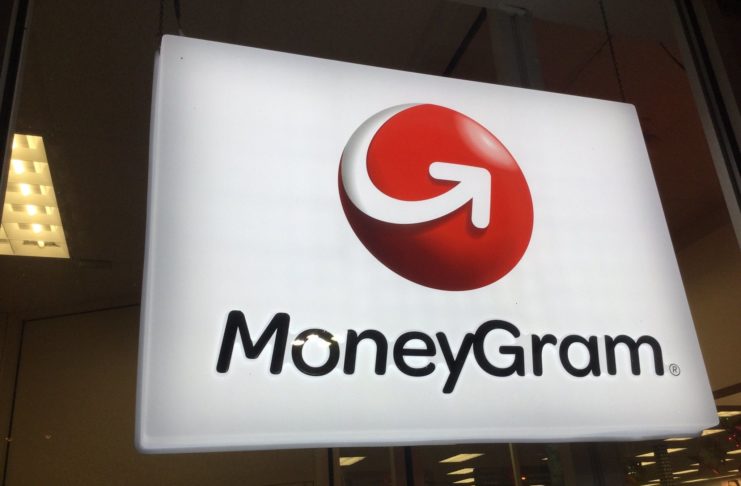 Glowing MoneyGram sign hanging from the ceiling, with an ATM behind it.