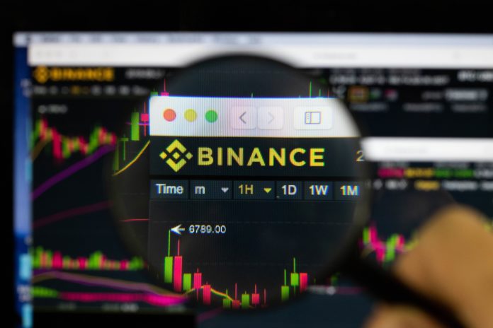 Binance logo on a monitor, looked through a magnifying glass.